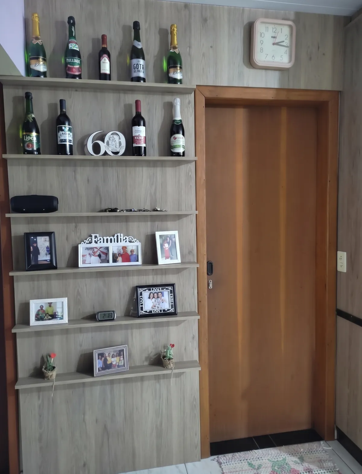 Painel de madeira com prateleiras para decoração, ao lado de uma porta