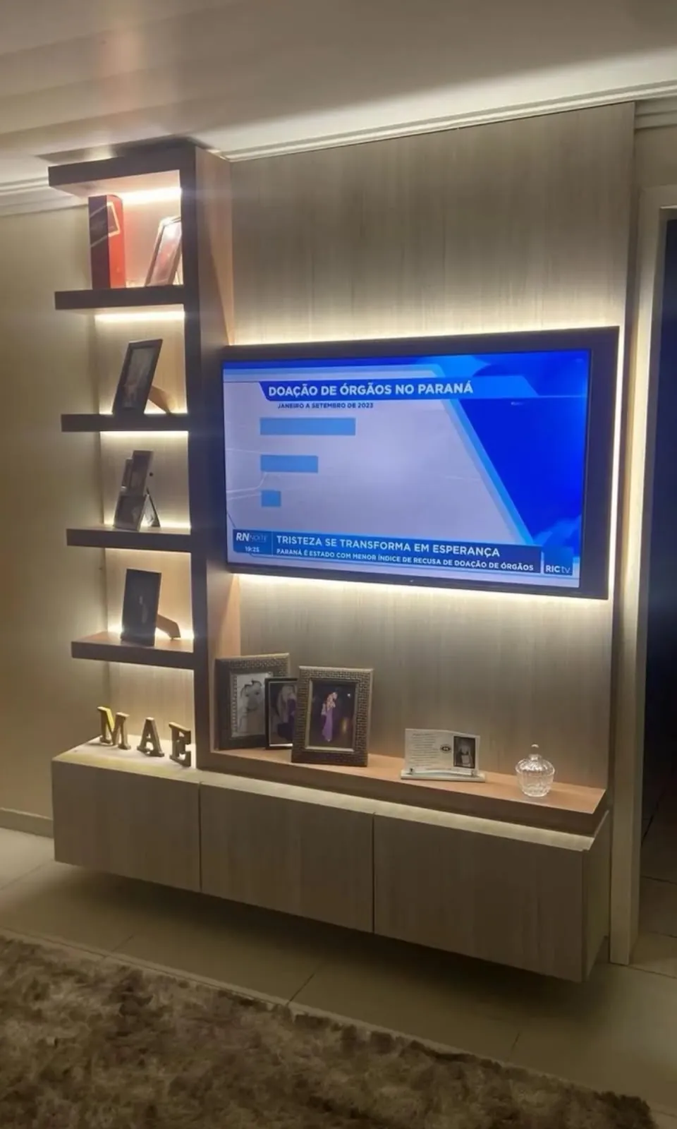 Painel de TV com nichos, fotos decorativas e iluminação de LED em sala de estar
